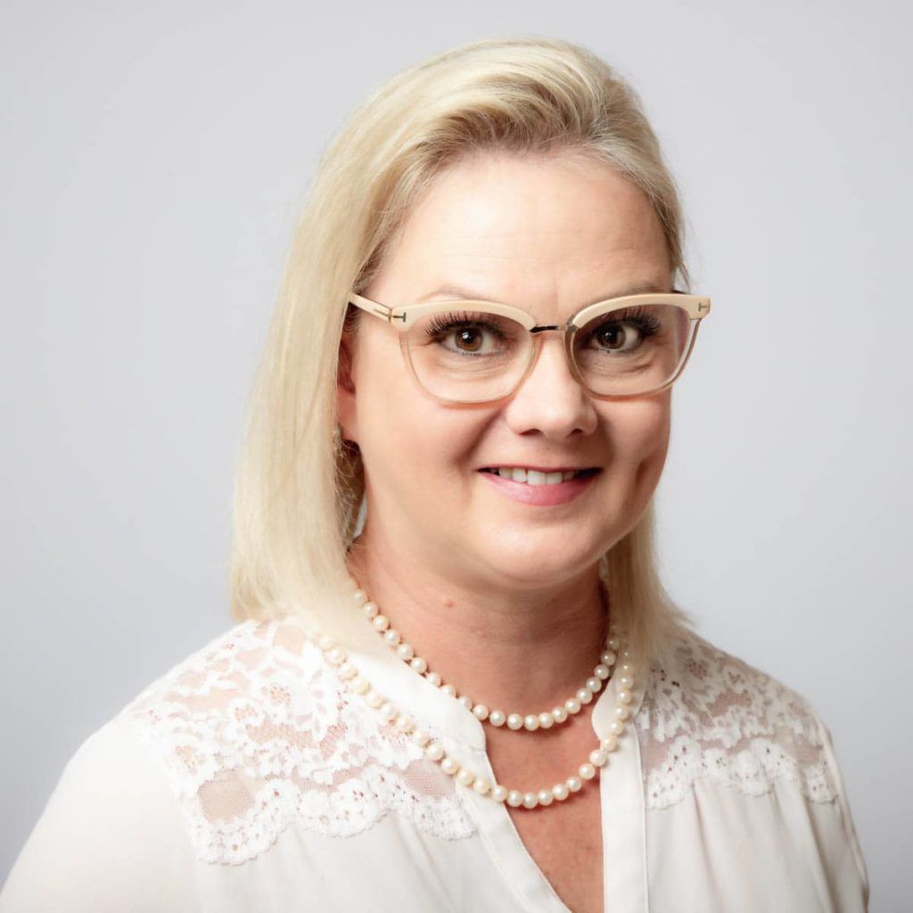 A woman wearing glasses and pearl necklace.