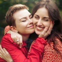 Two women embracing in the wilderness.