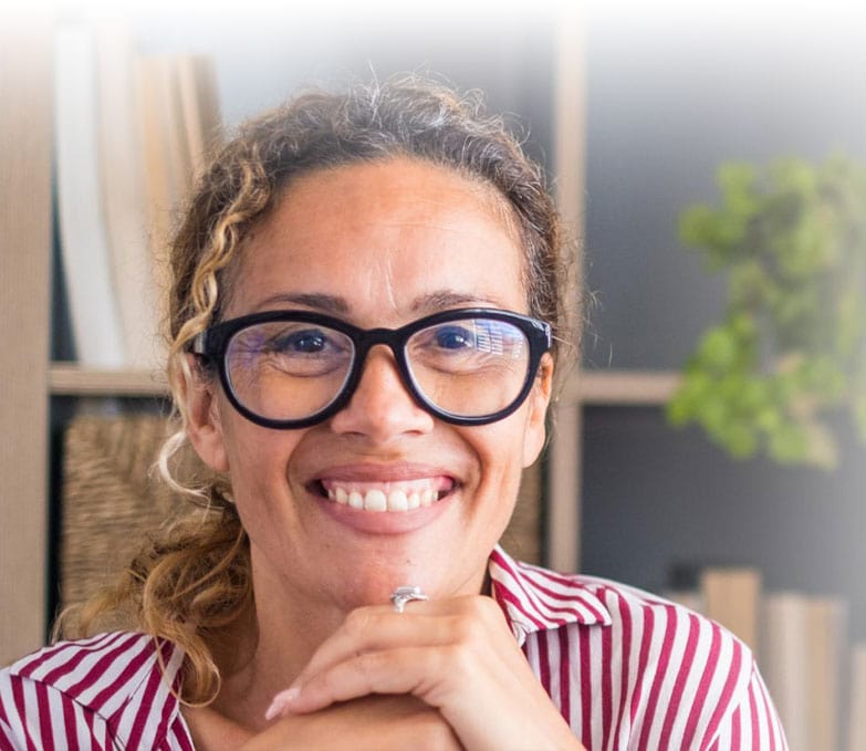 A woman wearing glasses smiles while holding the Attachment Styles Questionnaire.