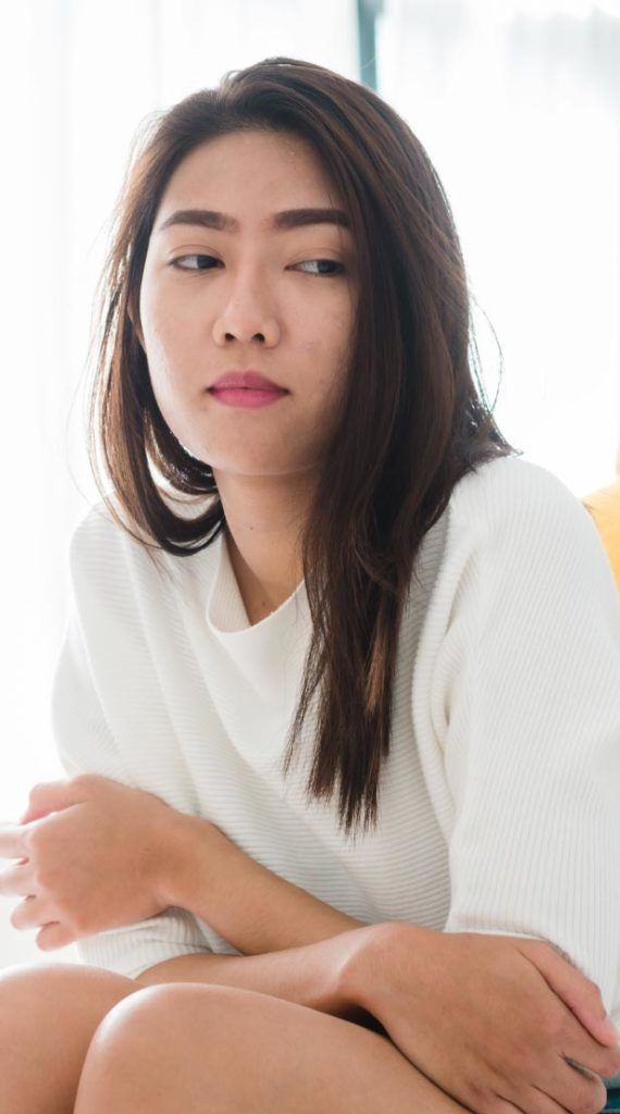 A young asian woman sitting on a couch.