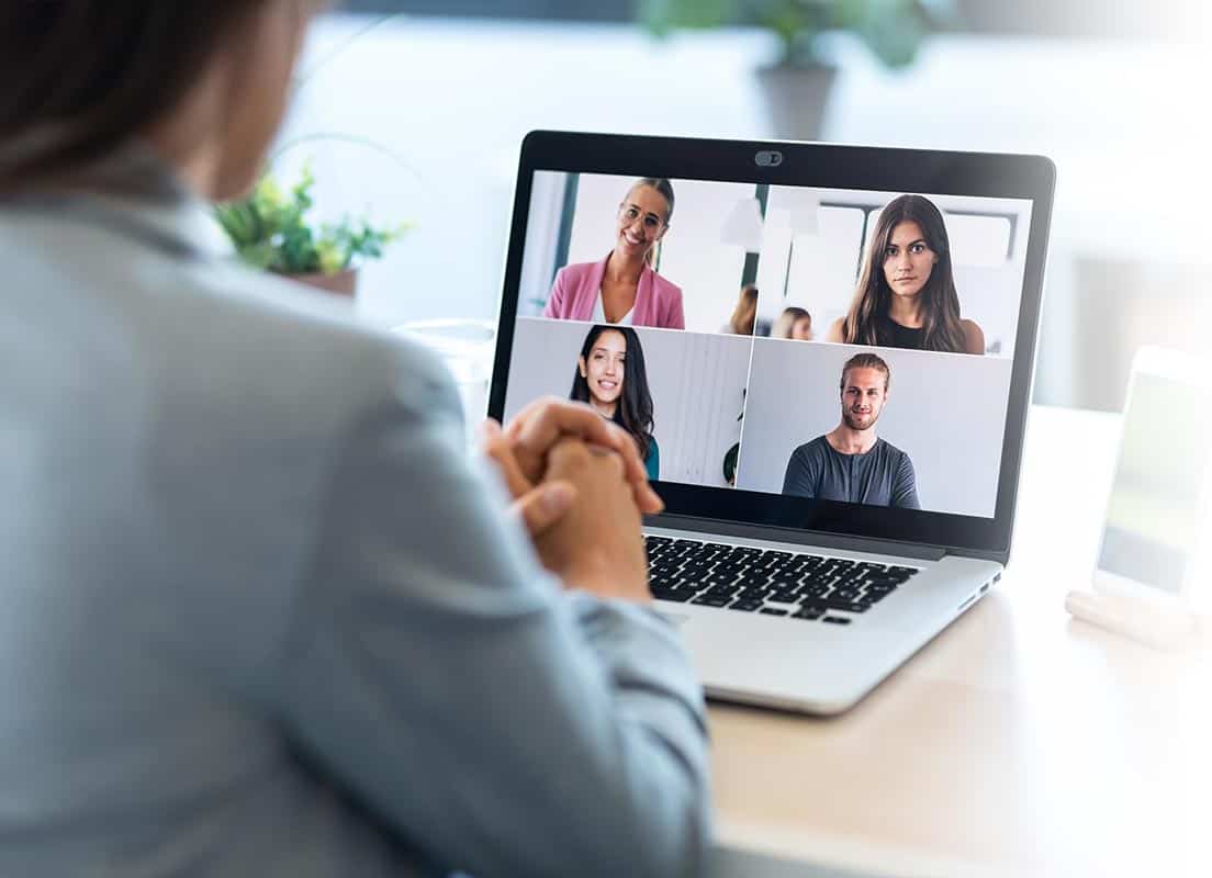 Trauma Solutions: Person sitting at a desk participating in a video call with four other people, all visible on a laptop screen in a grid layout.