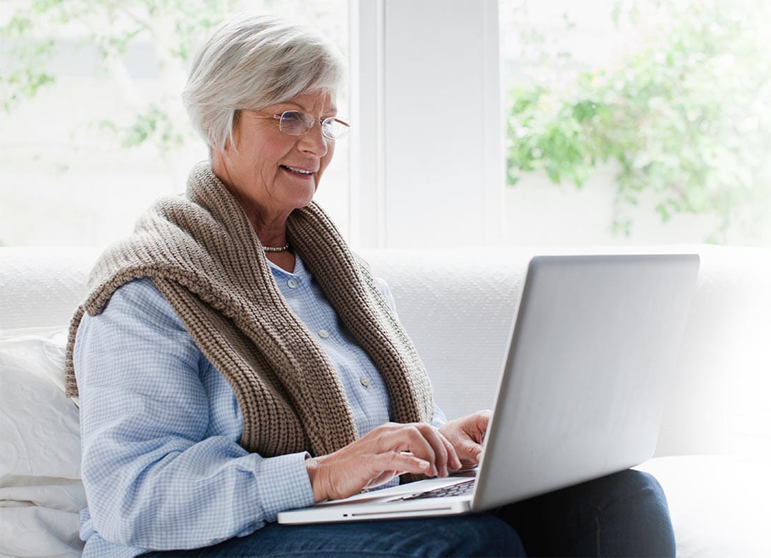 An older woman participating in Case Consult Group Training with Jennifer Jonell while using a laptop.