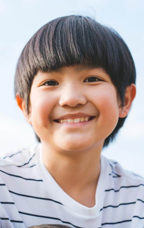 A young boy smiles while holding a dog, demonstrating an attachment bond.