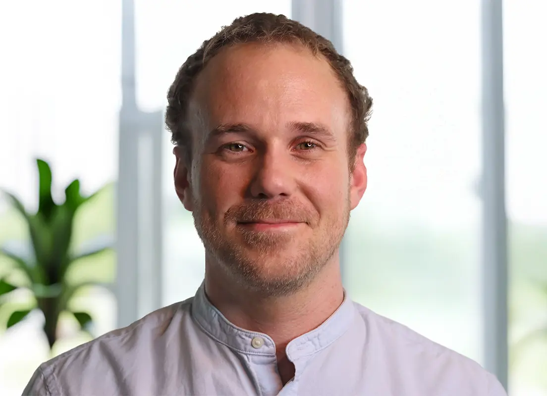 Trauma Solutions: A headshot of a smiling man with short brown hair and a light beard, wearing a pale blue collared shirt.