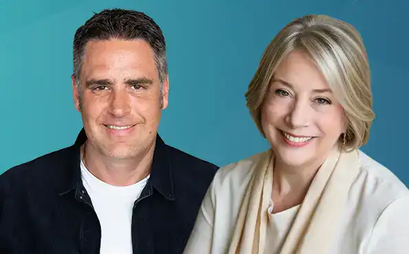 Trauma Solutions: Two adults, one man and one woman, smiling and posing for a photo in front of a blue background.