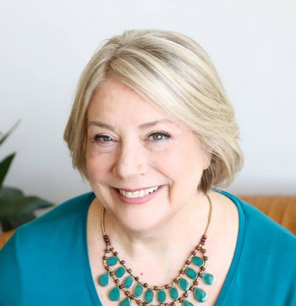 A woman incorporating the DARe approach wears a turquoise top and necklace with a smile.