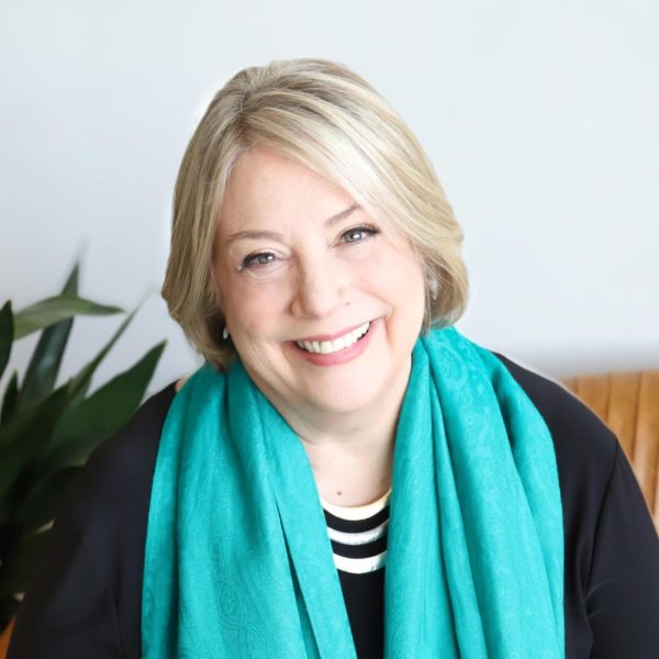 A smiling woman wearing a turquoise scarf.