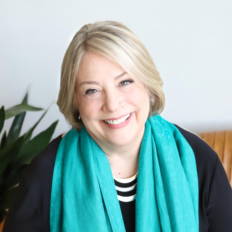 A smiling woman wearing a turquoise scarf.