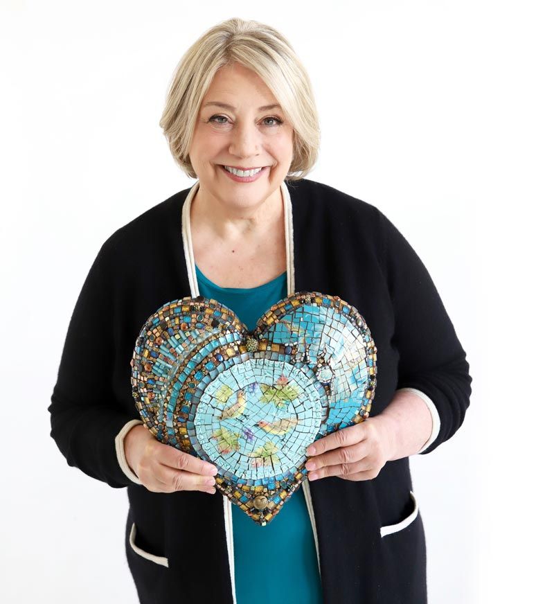 A woman holding a heart shaped mosaic.