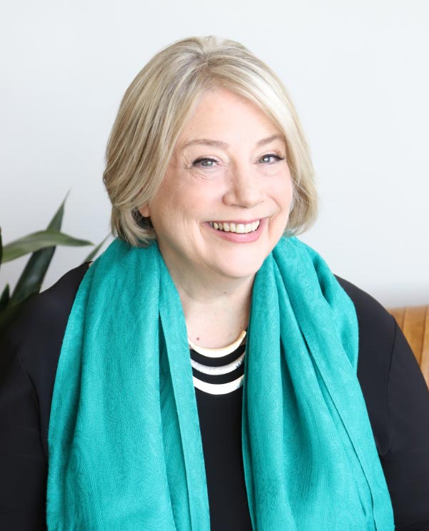 A smiling woman wearing a turquoise scarf.