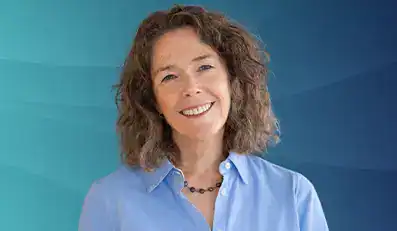 Trauma Solutions: Smiling woman with curly brown hair wearing a light blue button-up shirt and a beaded necklace, standing in front of a blue gradient background.