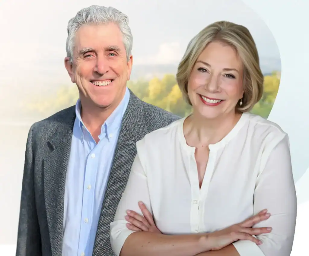 Trauma Solutions: A man in a grey blazer and a woman in a white blouse stand side by side, smiling in front of a blurred outdoor background.
