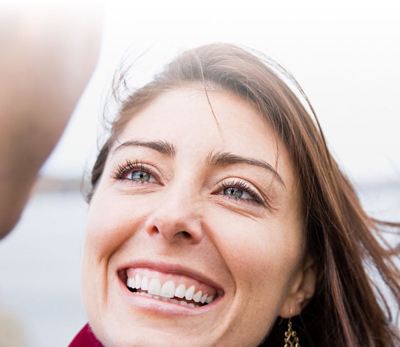 A therapist offers a comforting smile to her patient by a serene body of water.