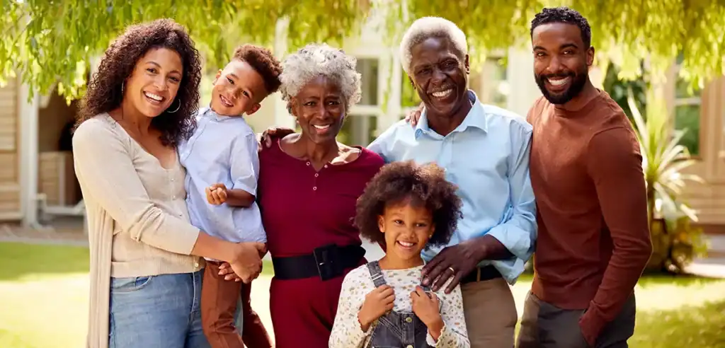 Trauma Solutions: Three adults and two children stand outside, smiling at the camera with trees and a house in the background.