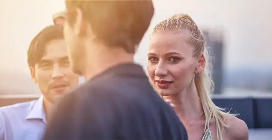 Trauma Solutions: Three people stand outside having a conversation; a woman with blonde hair looks directly at the camera while two men face away and towards her.