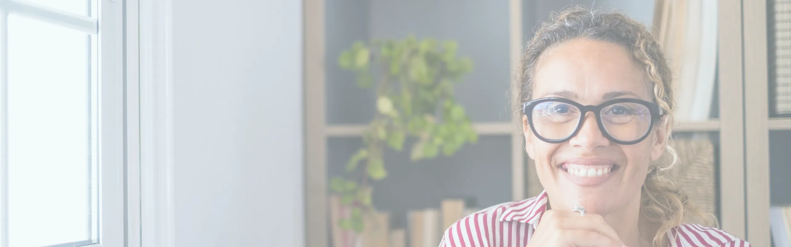 A female therapist smiles confidently with her hands clasped under her chin. Her warm expression embodies the qualities of the 8 Cs of Self in Internal Family Systems therapy—calmness, curiosity, clarity, compassion, confidence, courage, creativity, and connectedness—which provide the foundation for healing attachment trauma and discovering one's authentic Self.