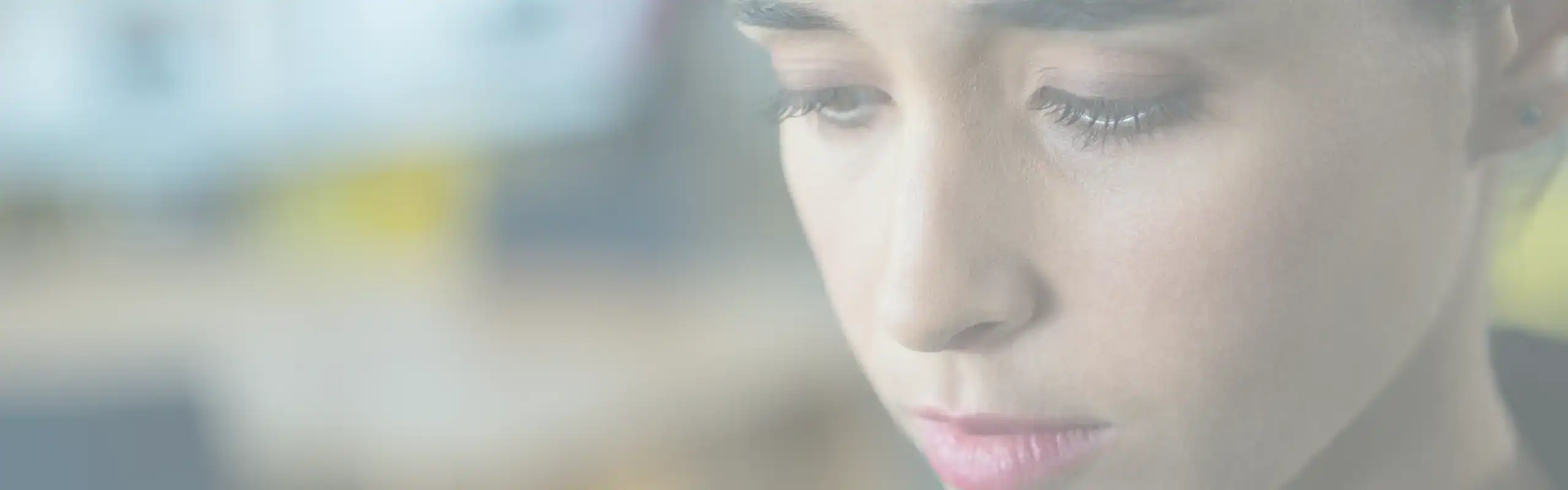 A woman looks downward with a pensive expression. Shame often presents in the body as a collapse, as a way of minimizing one’s presence.