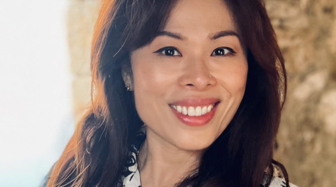 Jane Kwok-Yee Leung, an asian woman, smiling in front of a stone wall.