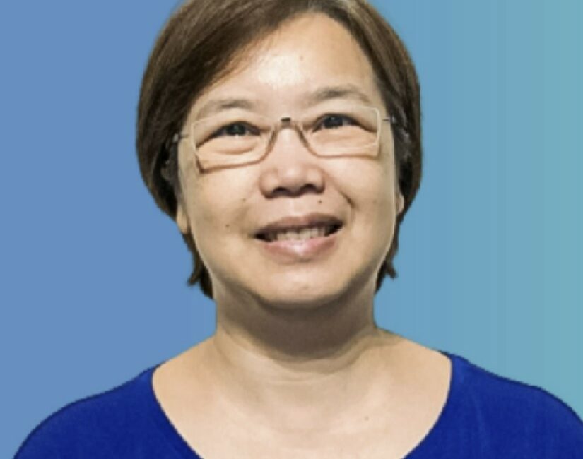 Trauma Solutions: A middle-aged woman with short brown hair and glasses smiles at the camera, wearing a blue top against a blue gradient background.