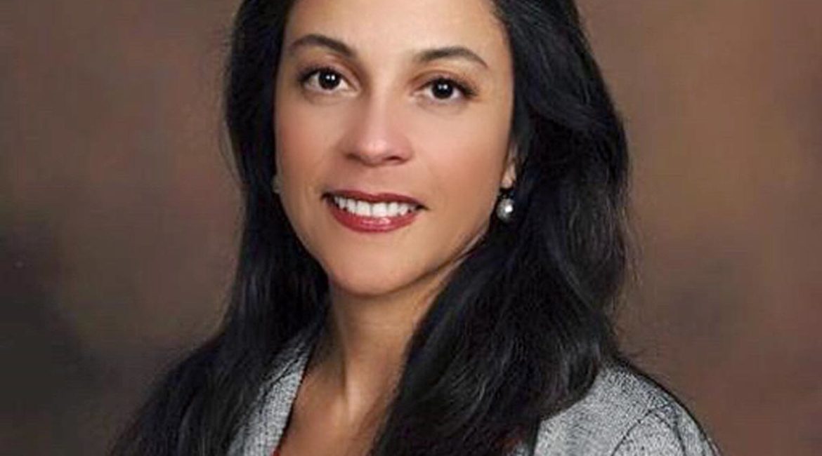 A woman wearing a gray jacket and red top.