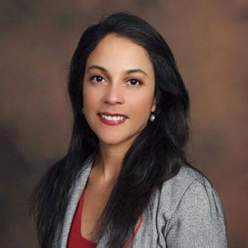 A woman wearing a gray jacket and red top.