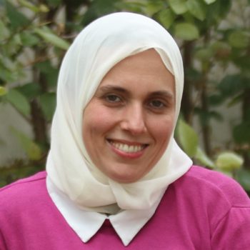 A woman wearing a white hijab smiles for the camera.