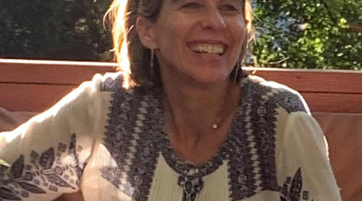 A woman smiles while sitting on a patio.
