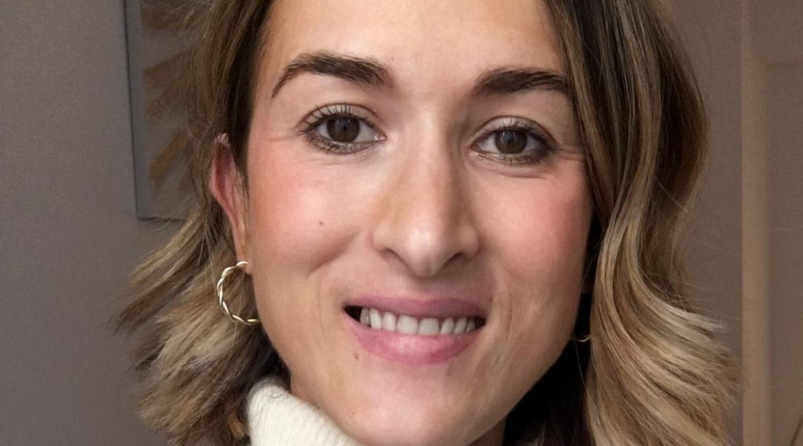 A woman is taking a selfie in a white sweater.
