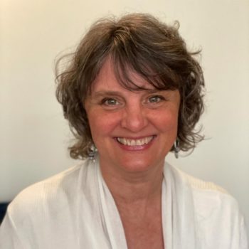 A smiling woman wearing a white robe.