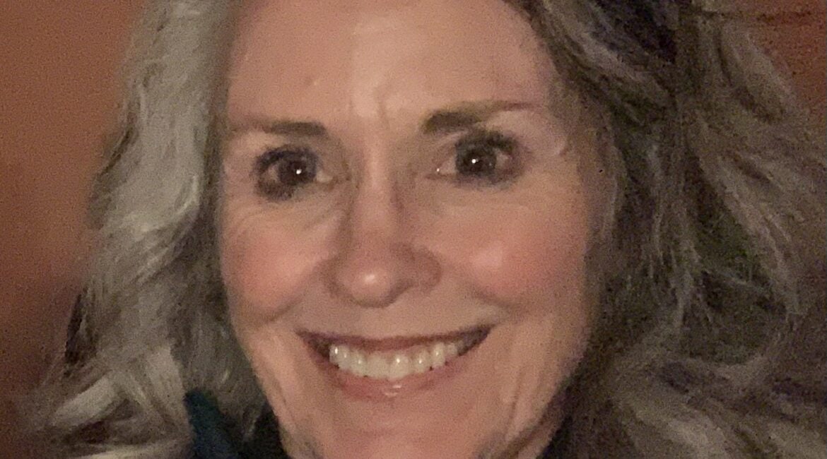 A woman with gray hair smiling for the camera.