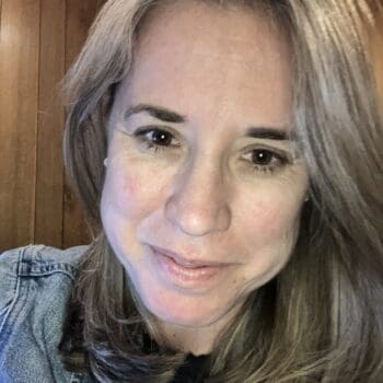 A woman in a denim jacket smiling at the camera.