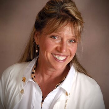 A smiling woman in a white jacket.