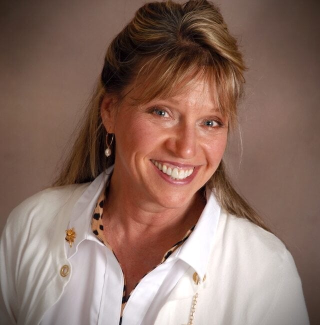 A smiling woman in a white jacket.