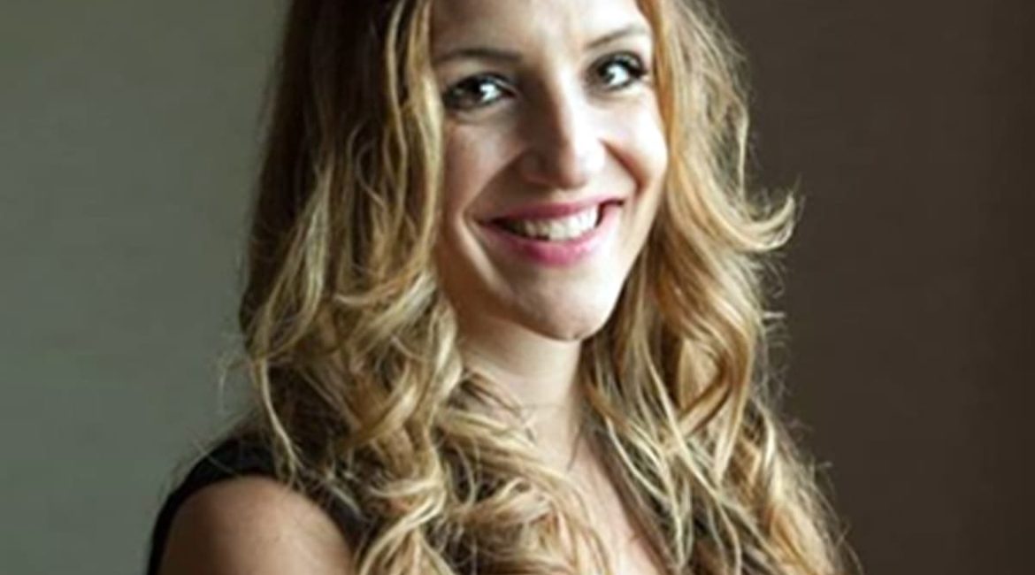 A woman in a black top smiling for the camera.