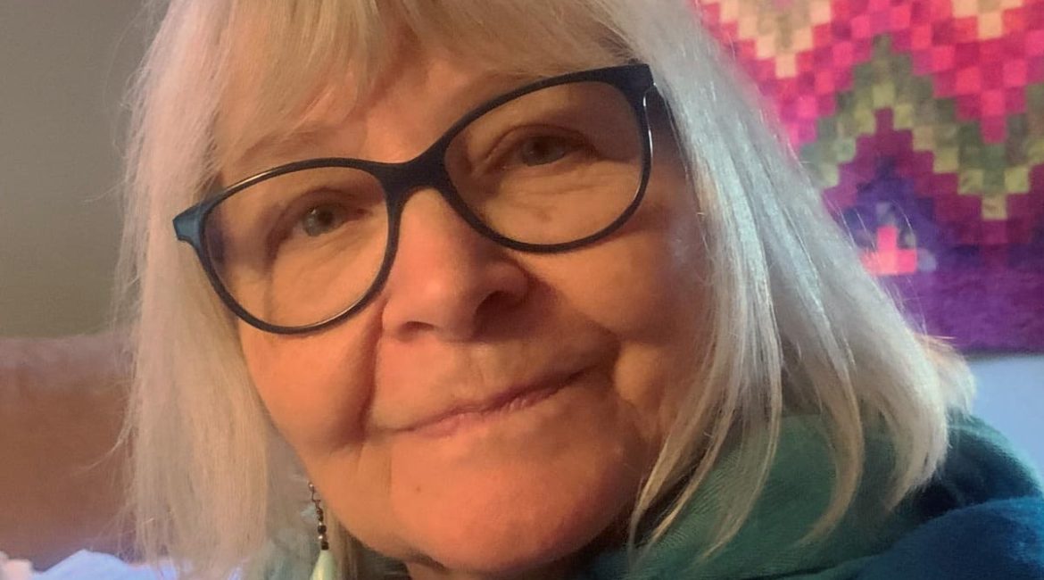 An older woman wearing glasses and a blue scarf.
