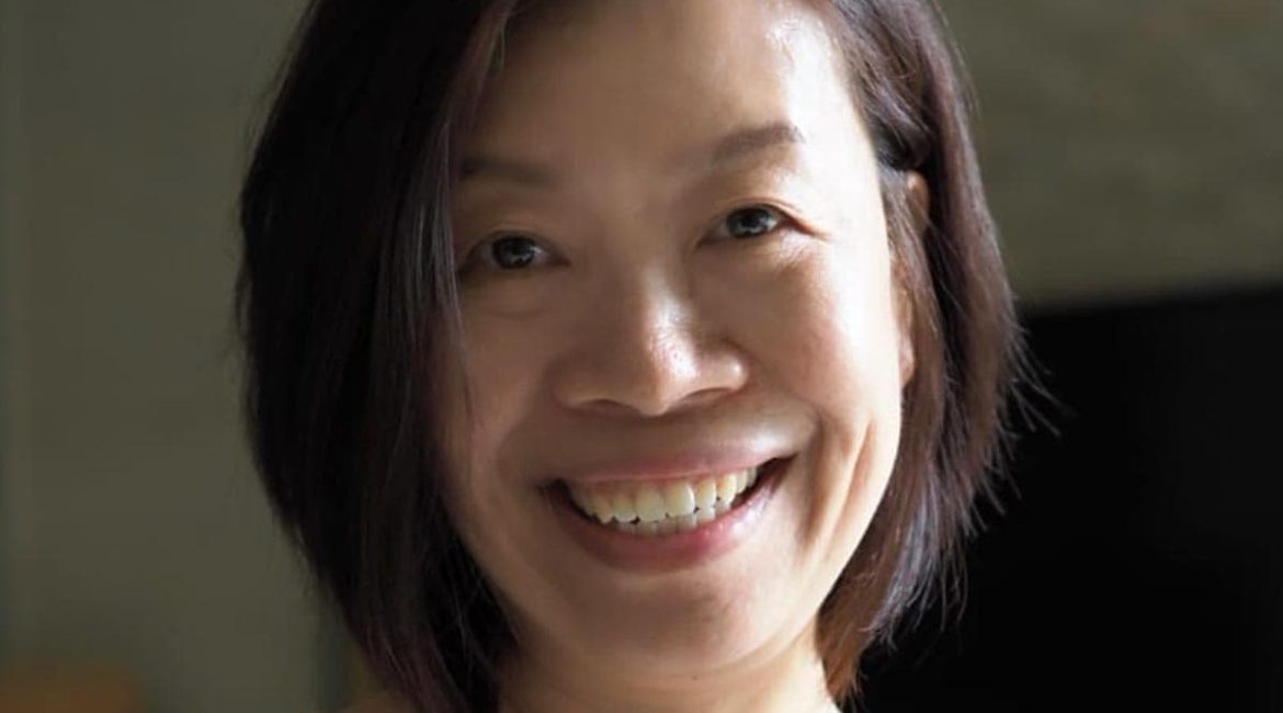 A smiling asian woman in a floral dress.