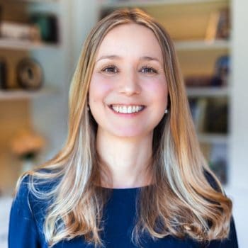 A woman smiling in front of a bookshelf.