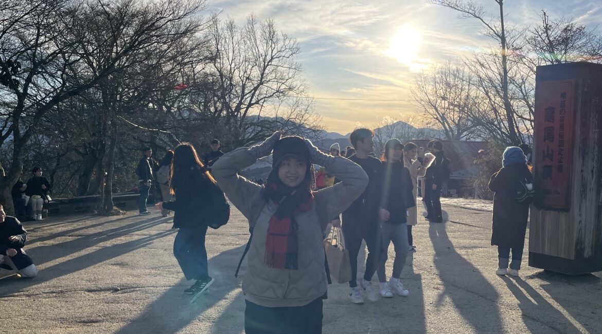 Trauma Solutions: Person standing in sunlight with hands on head, surrounded by people casting long shadows on a paved area, leafless trees and blue sky in the background.