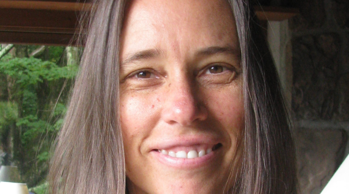 A woman with long brown hair is smiling.