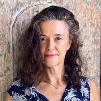 A woman with curly hair standing in front of a wooden door.