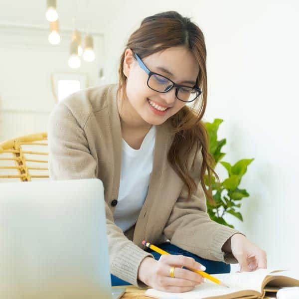 A young Asian woman journaling at home, exploring trauma solutions.