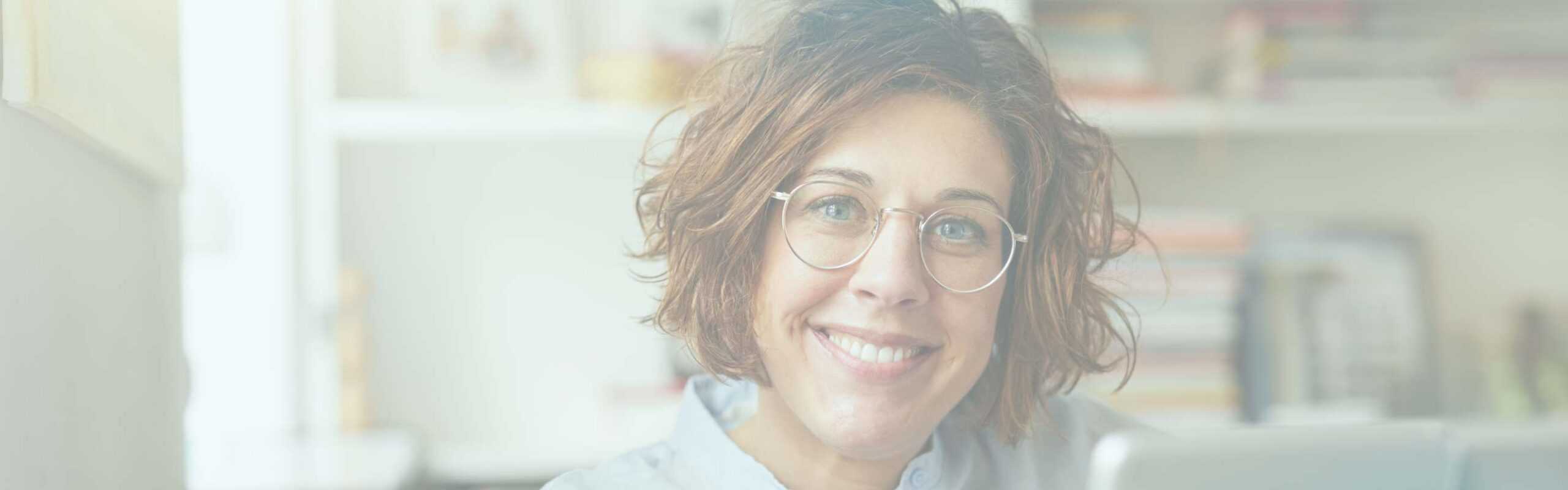 A therapist in her office smiles warmly towards the camera, demonstrating a safe and secure attachment