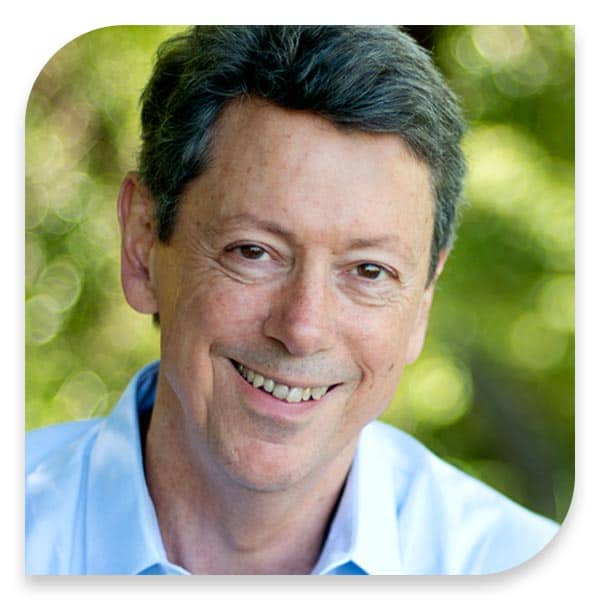 A man in a blue shirt smiling for the camera, holding The Power Attachment Book.