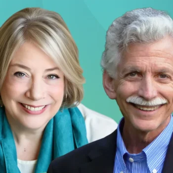 Trauma Solutions: Two smiling older adults, a woman with short blonde hair and a teal scarf, and a man with curly gray hair, mustache, and a navy blazer, pose together against a teal background.