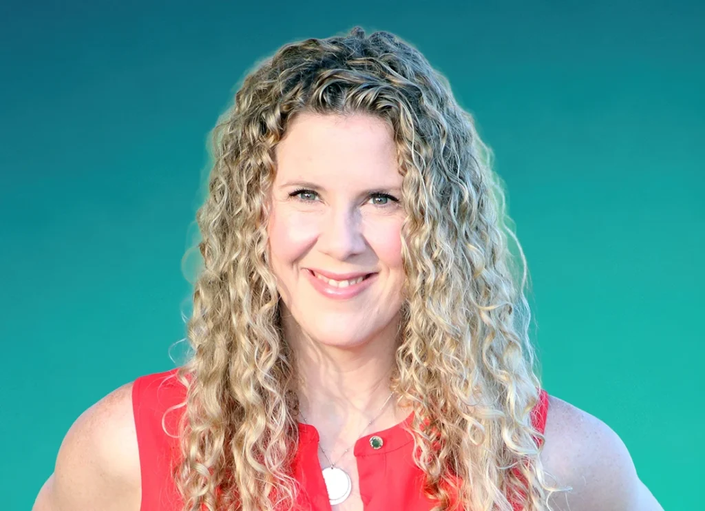 Trauma Solutions: A woman with long curly hair smiling at the camera.