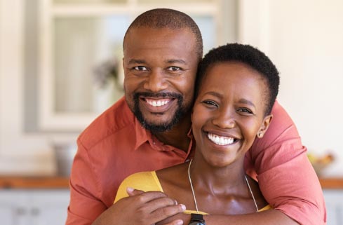 A black man and woman hugging in the kitchen.