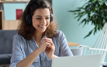 DARe Intensives: A woman wearing headphones is focused on her laptop during a live session.