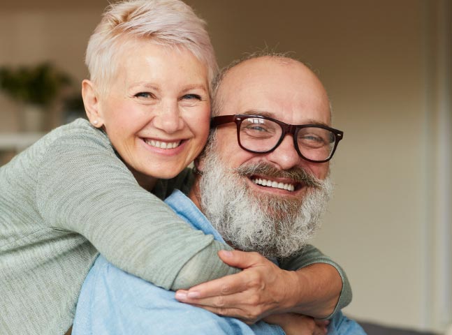 An older man and woman hugging each other.