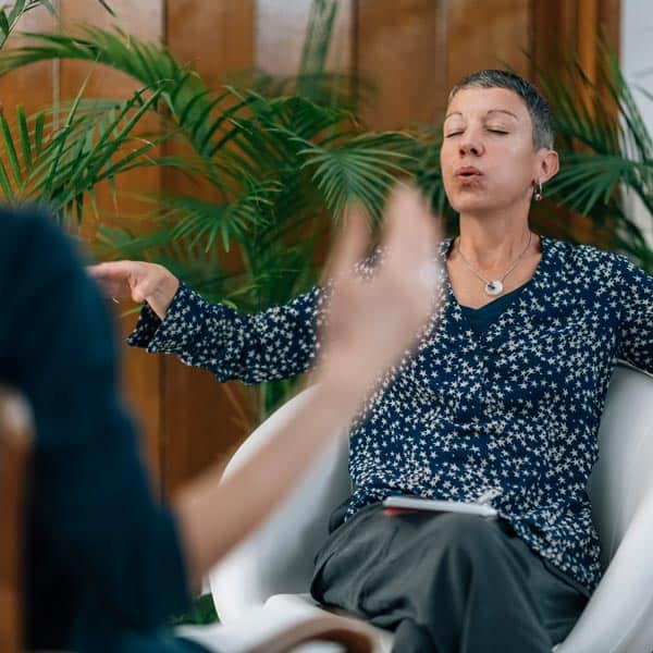 A woman utilizing the DARe Approach engages in a conversation with another woman while seated in a chair.