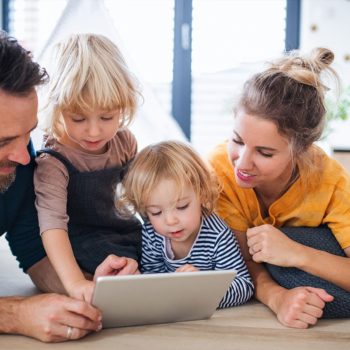 A family looking at a tablet while sitting on the floor.